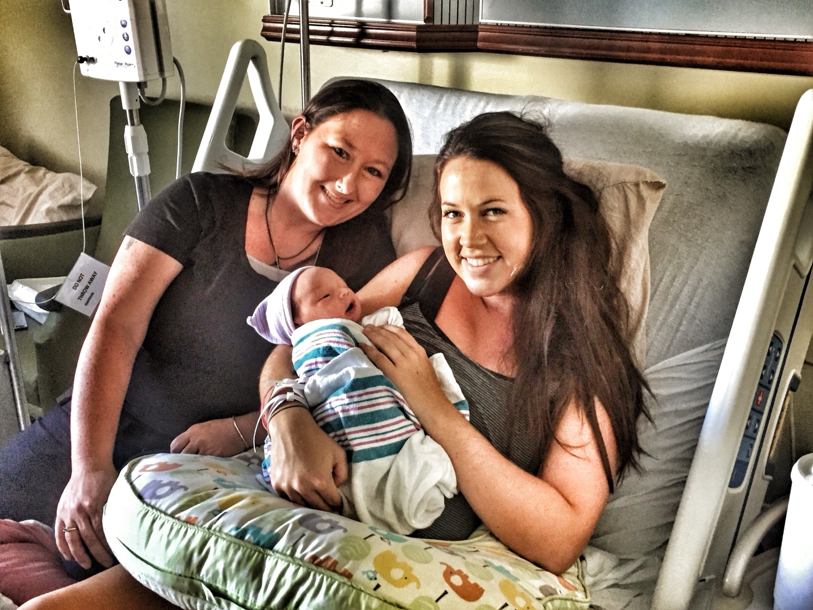 Kristie and a new mom smiling together with her newborn