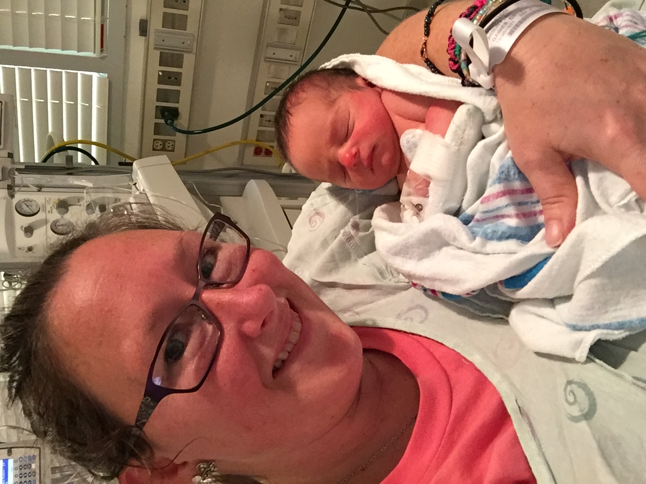 Kristie in glasses holding baby Jeremiah in a hospital room